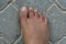 Close up of women`s foot isolated on a concrete floor background. Foot is ugly, dark brown and it has hair and veins showing. No