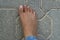 Close up of women`s foot isolated on a concrete floor background. Foot is ugly, dark brown and it has hair and veins showing. No