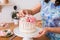 Close-up of women`s hands decorating the cake with fresh flowers