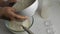 Close-up of women`s hands sifting flour into a transparent bowl with kefir and eggs