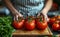 Close-up women are tomatoes. A person skillfully cuts ripe tomatoes on a wooden cutting board