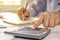 Close-up of women using a calculator and note-taking of accounting reports.