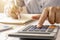 Close-up of women using calculators and note-taking, accounting reports.