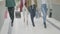 Close up of women wearing different clothing styles and shoes walking in mall holding shopping bags -