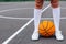 Close up wonan`s feet in white sneakers and whote long socks, with a ball on a basketball court