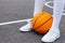 Close up wonan`s feet in white sneakers and whote long socks, with a ball on a basketball court