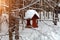 Close-up of a wooden birdhouse bird feeder covered with a large layer of snow on a clear winter day in a forest suspended from a