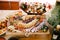 Close-up of a wooden cutting board with meat and cheese cuts, a grape cube and kitchen scissors on a background of salad