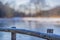 Close-up of a wooden fence surrounding a pond with its frozen waters