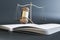 Close up of wooden gavel, scales and book/journal on gray background. Lawyer, justice and punishment concept.