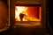 Close up of wooden logs burning in wood burning fire with open door in home living room.
