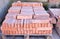 Close up of a wooden pallet plenty of old stacked red bricks. The bricks are ordered in many rows