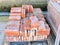 Close up of a wooden pallet plenty of old stacked red bricks. The bricks are ordered in many rows