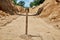 Close-up of a wooden stake for setting the height of the base of the pipeline laying in the trench, sand rammed base