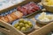 Close up of a wooden tray filled with spanish tapas with olives, cheese, smoked sausage, slices of ham and a bowl of crisps