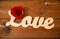 Close up of word love cutout with red rose on wood