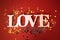 Close up of the word Love on a red background. Bright backdrop with silver sequins and golden round confetti