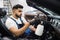 Close up of worker of auto service station, cleaning modern vehicle interior with tornado air gun.