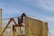 Close up of a worker in holding plank installing it on household construction using air hammer in nailing wooden beams.