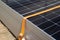 Close-up of a worker\\\'s hands tying a stack of solar panels with orange webbing