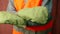 Close-up of a worker in uniform wearing mittens in an orange vest with reflective stripes gesturing with his hands to stop work.