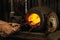 Close-up working powerful hands of male blacksmith making red hot metal in furnace, horn. Work process of heating metal