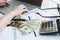 Close up of working woman hand using laptop computer on office desk with money report paper eyeglasses and calculator. Business