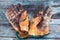 Close up of worn leather work gloves on wood background, stained with grease and industrial oil