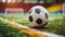 Close-up of a worn soccer ball on a grass field with a colorful blurred background.