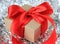 Close-up wrapped vintage gift box with red ribbon bow on silver sparkly background