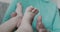 Close-up wrinkled hands of grandmother holding the soft legs of a newborn.