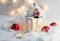 Close up of Xmas lantern with candles and red cozy balls. Christmas decoration on white fur. Shallow depth of field and bokeh.