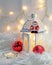 Close up of Xmas lantern with candles and red cozy balls. Christmas decoration on white fur. Shallow depth of field and bokeh.