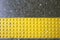 Close up yellow braille block on dark granite tile floor