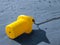 Close up of a yellow buoy on the blue sand beach chained to the