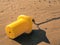 Close up of a yellow buoy on the yellow sand beach chained to th