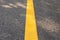 Close up yellow line on concrete road with rough surface under sunlight in the park shows concept of sign for driving lane,