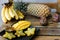 Close up yellow mango with carambola on plate near pine-apple and bananas on wooden table.