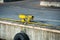 Close-up of yellow metallic mooring column or bollard on the edge of stone quay blue water background. Marine Bollard column with