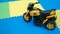 Close up of yellow motorcycle toy on rubber floor with copy space at playground.