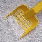 Close-up of a yellow plastic shovel on cat litter.