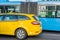 Close-up of yellow taxi near blue bus. Bus or taxi. City transportation and vehicle selection concept