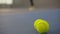 Close-up of yellow tennis balls lying on the floor in gym with blurred Caucasian sportswoman serving at the background