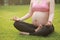 Close-up yoga gesture pregnant woman sit in meditation on grass meadows on sunny sunshine sunset sunrise nature outdoor