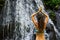 Close up of yoga woman raising arms with namaste mudra in front of waterfall. View from back. Pucak Manik waterfall Wanagiri, Bali