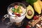 Close up yogurt with granola and fruits in glass on black granite stone