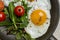 Close up yolk on pan with salad and cherry tomatoes