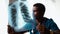 Close-up of young African American man doctor wearing surgeon medic suit studying chest X-Ray image.