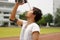 Close up young Asian runner pouring water with waterbottle on his face after running on track.