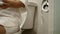 Close-up of Young Asian woman sitting on toilet bowl and using toilet paper. Health care concept.